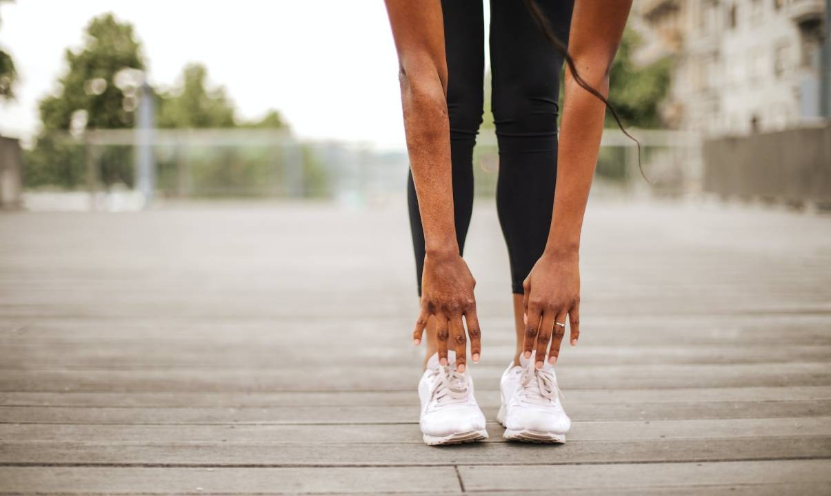 A woman stretching and touching her toes on a boardwalk