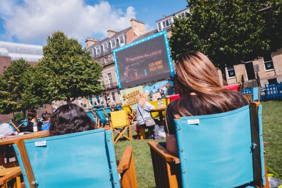People sitting on chairs at screen on the green