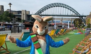 A person in a rabbit costume standing on Newcastle’s Quayside with the Tyne Bridge in the background