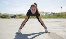 A woman dressed in black exercise wear warming up in a car park